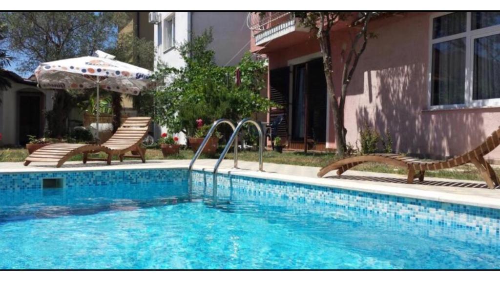 a swimming pool with two chairs and an umbrella at Hestia Apartments in Rovinj