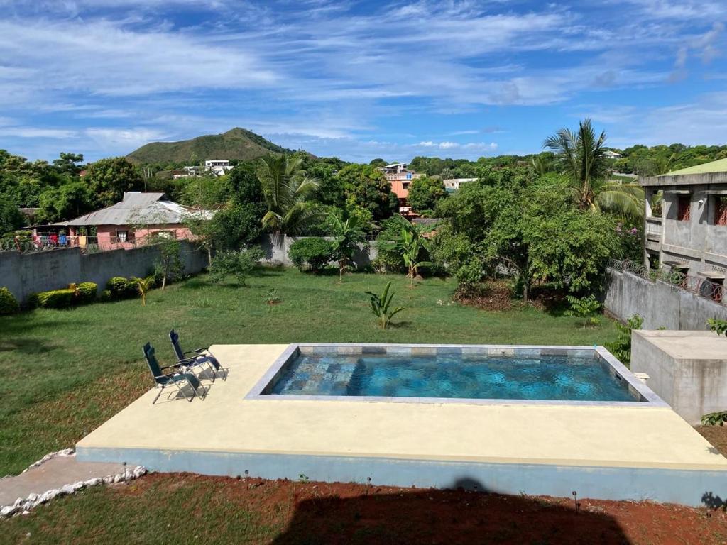 einen Pool in einem Garten mit zwei Stühlen in der Unterkunft VILLA RAVOLA - Ambondrona in Nosy Be