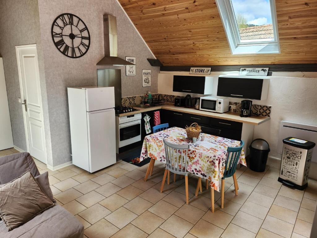 a kitchen with a table and a white refrigerator at le nid du calice in Abreschviller