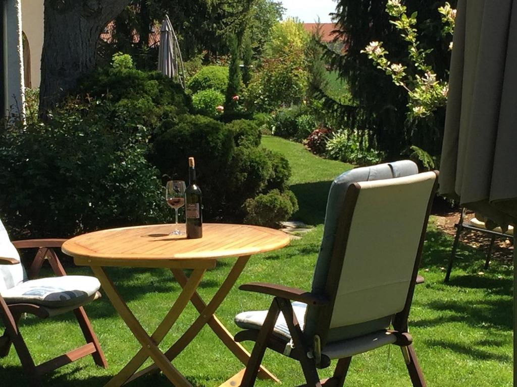 a table with a glass of wine and two chairs at Ferienwohnung Schmidbauer in Beilngries