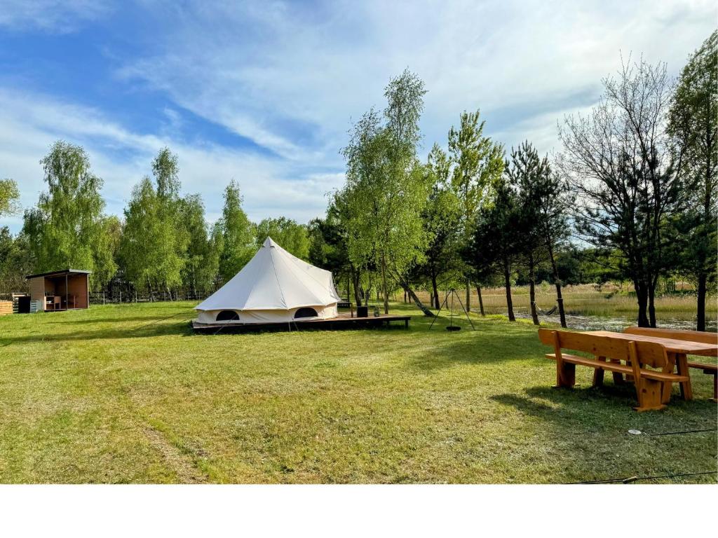 una tienda blanca en un campo con un banco en Glampine, en Chocianów