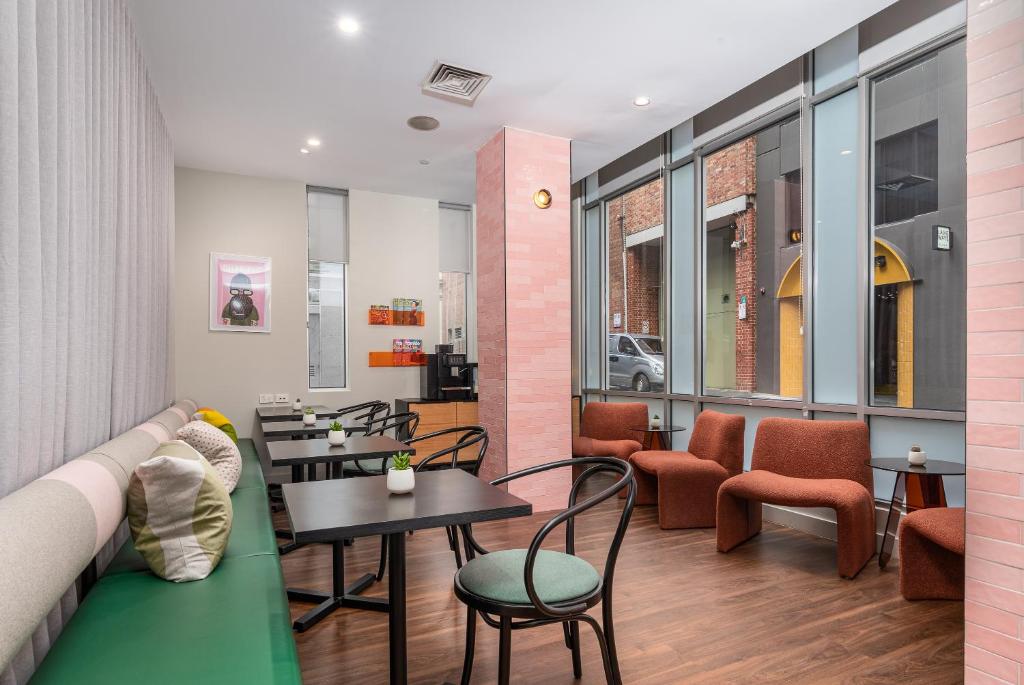 a restaurant with a couch and tables and chairs at City Limits Hotel Apartments in Melbourne