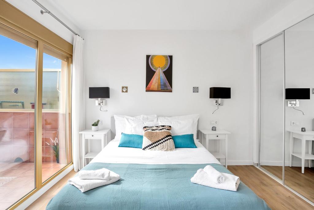 biała sypialnia z dużym łóżkiem z niebieską pościelą w obiekcie Modern beach apartment Romana Playa 723 in Marbella, Elviria w Marbelli