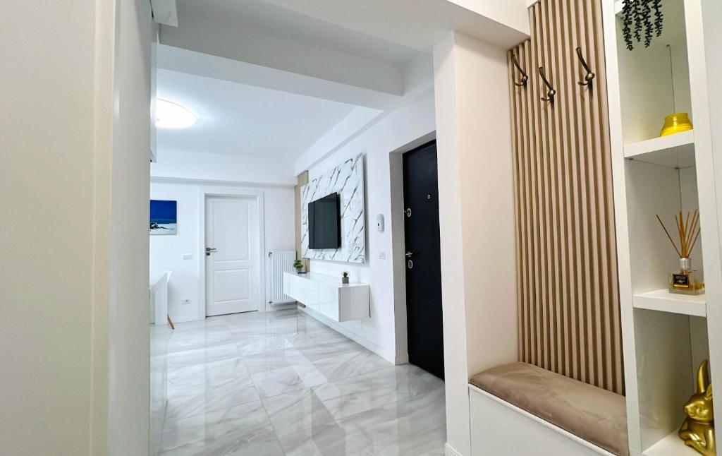 pasillo con paredes blancas, suelo blanco y TV en Zain Apartment en Craiova
