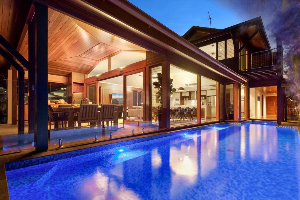 a swimming pool in front of a house at 23 The Cove - Whitsunday Waterfront Living in Airlie Beach
