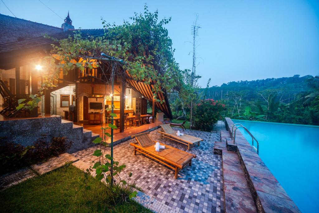 une arrière-cour avec une piscine et une maison avec une table et des bancs dans l'établissement Villa Dandan Bukit, à Gianyar