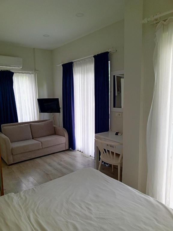 a bedroom with a couch and a desk in a room at Port Hotel, Tasucu in Silifke