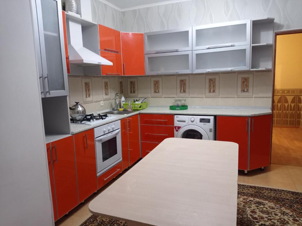 a kitchen with red cabinets and a washing machine at Квартира in Aktobe