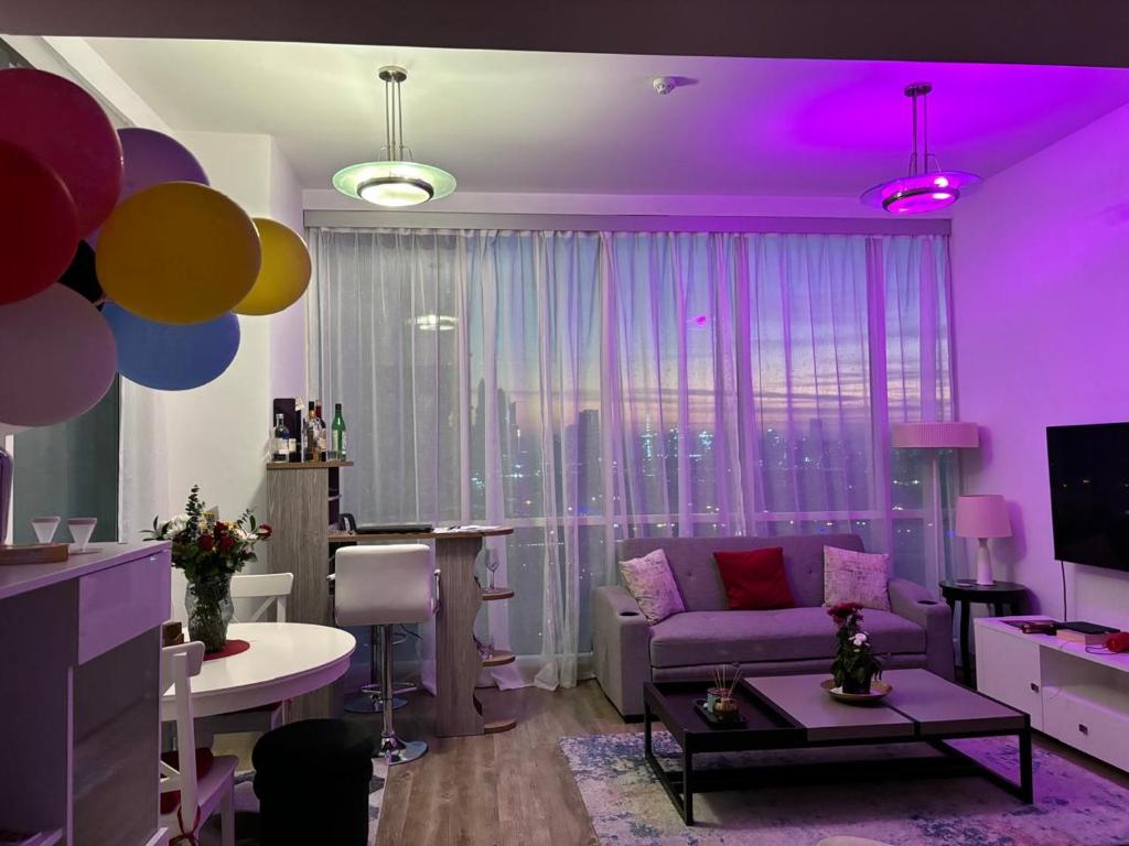 ein Wohnzimmer mit lilafarbener Beleuchtung und einer Couch in der Unterkunft Apartment in Al Sufouh 1st - Comfortable Home with 5 iconic views in Dubai