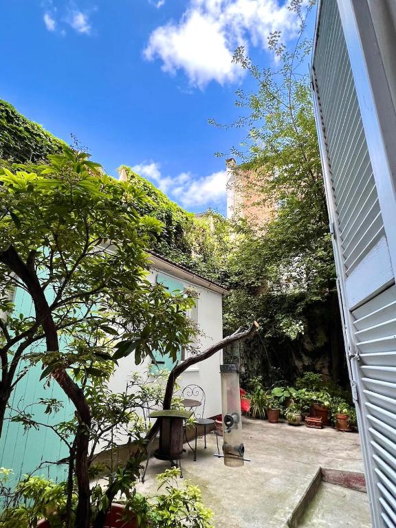 un patio avec une table et un arbre à côté d'un bâtiment dans l'établissement Charming Montmartre Studio, à Paris