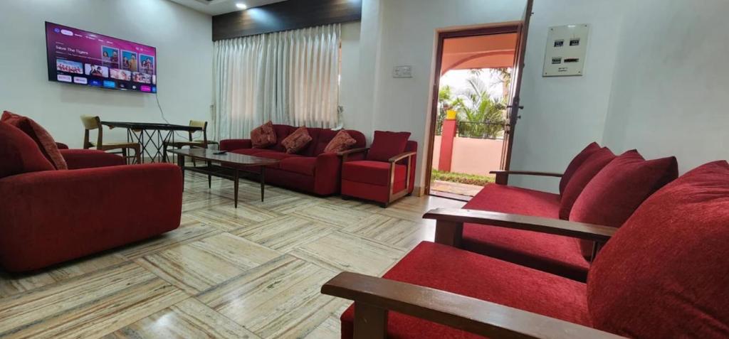 a living room with red couches and a table at Gracias Villa in Panaji
