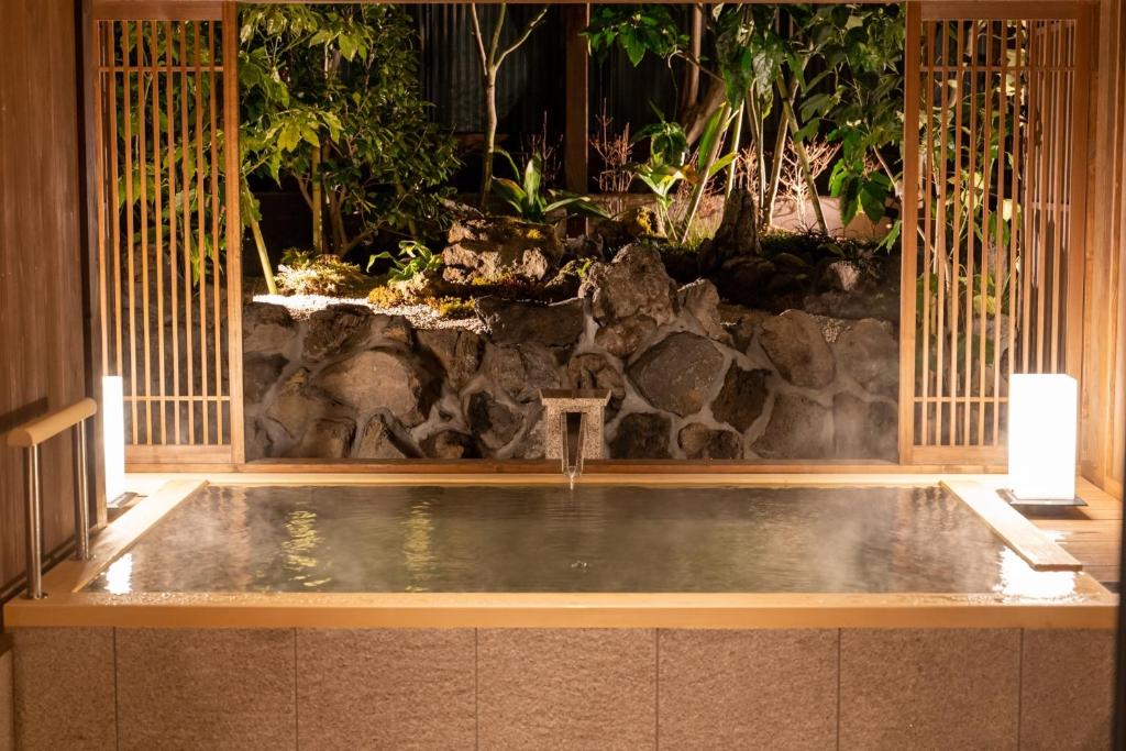 Atami Onsen Hotel Yume Iroha في أتامي: حمام سباحة بحائط حجري و سطحي غير مريح