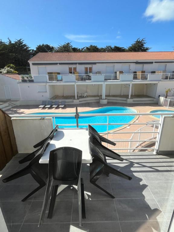 un patio avec deux chaises et une piscine dans l'établissement T2 avec piscine à 400m de la plage, à Saint-Jean-de-Monts