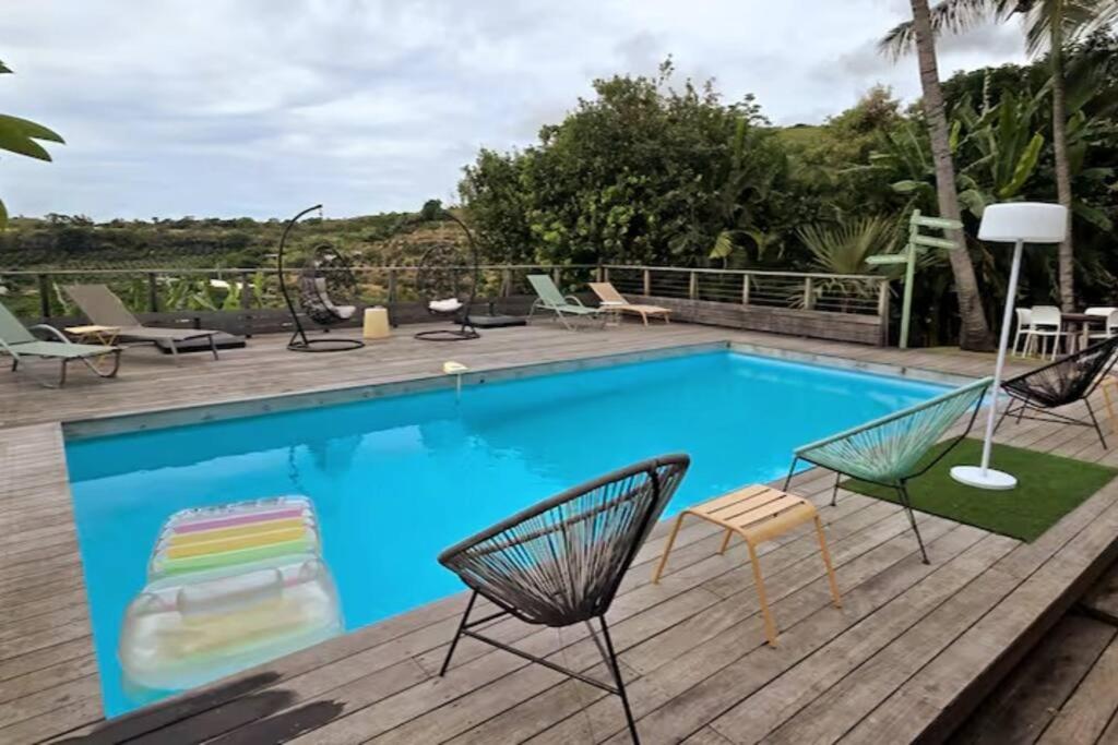 Una gran piscina con sillas y una mesa. en La Baie des Mangues 3 - Ylang-Ylang - Nibou, en Saint-Paul