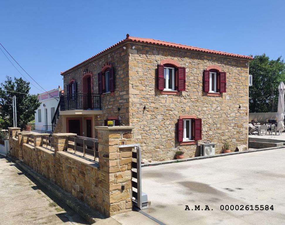 a stone building with red windows on a street at Lucy's luxury II in Néa Koútali