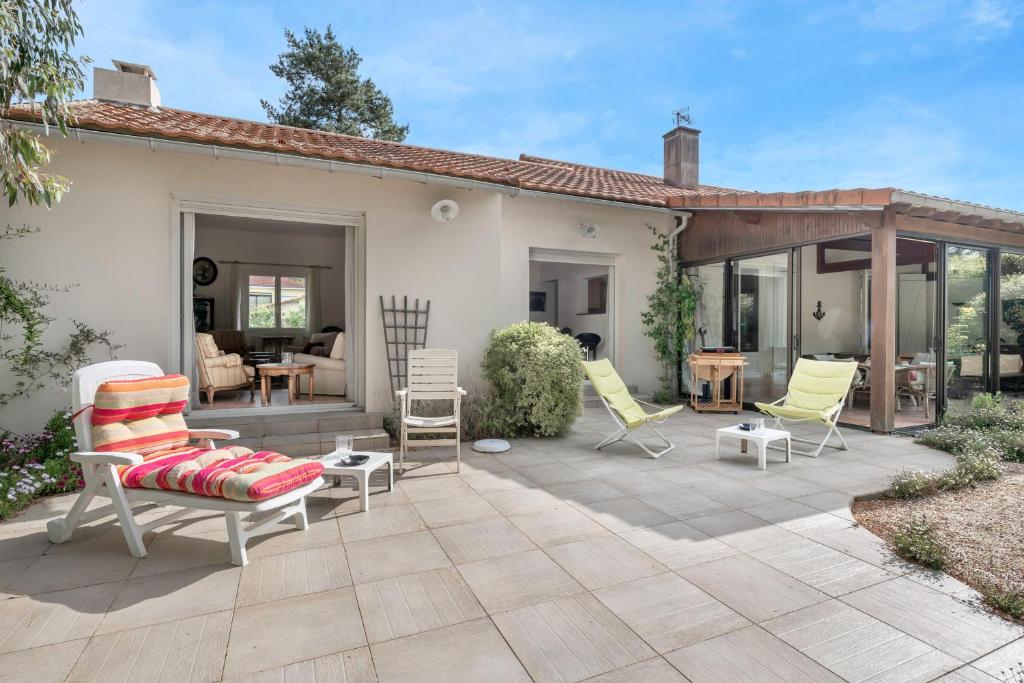 un patio avec des chaises et une table et une maison dans l'établissement Maison avec jardin pour 6 à St Brévin L’Océan, à Saint-Brévin-les-Pins