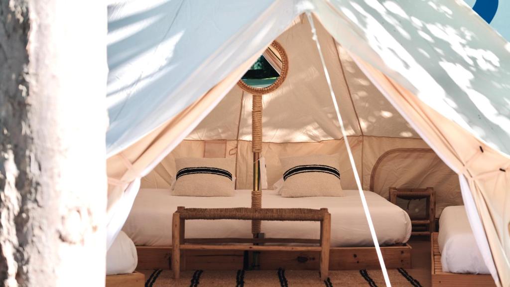 - un lit dans une tente en toile avec une chaise dans l'établissement HolaCamp Vendrell, à Coma-ruga
