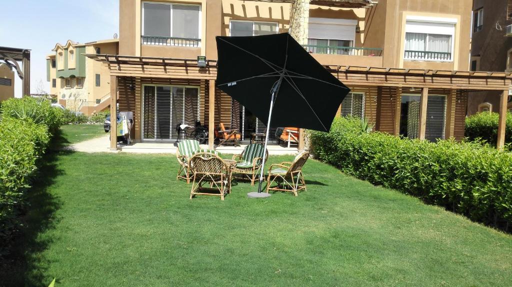 a table and chairs with an umbrella in the grass at Three-Bedroom Garden Chalet at Marina Wadi Degla For Families in Ain Sokhna