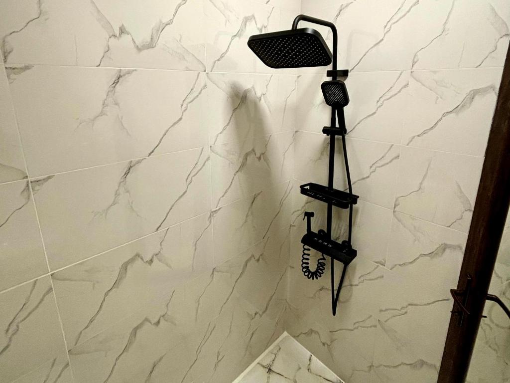 a shower with a white marble wall at Wayside Cottage in Batumi