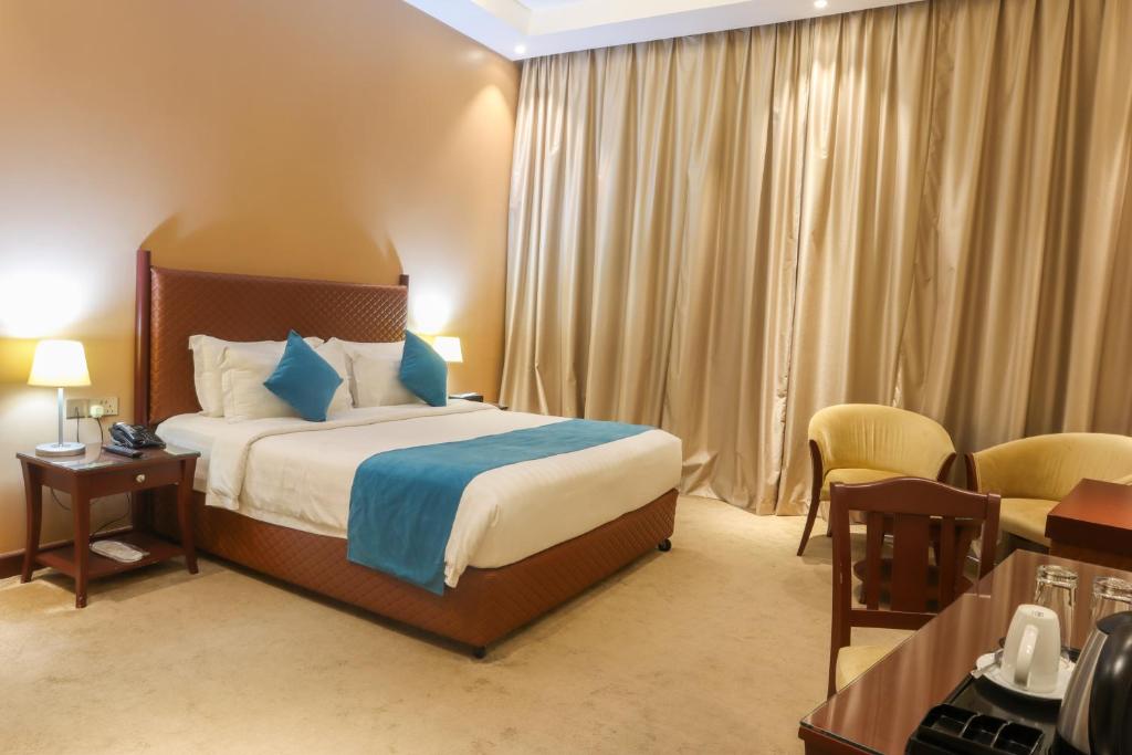 um quarto de hotel com uma cama e uma secretária em Happy Days Hotel em Manama