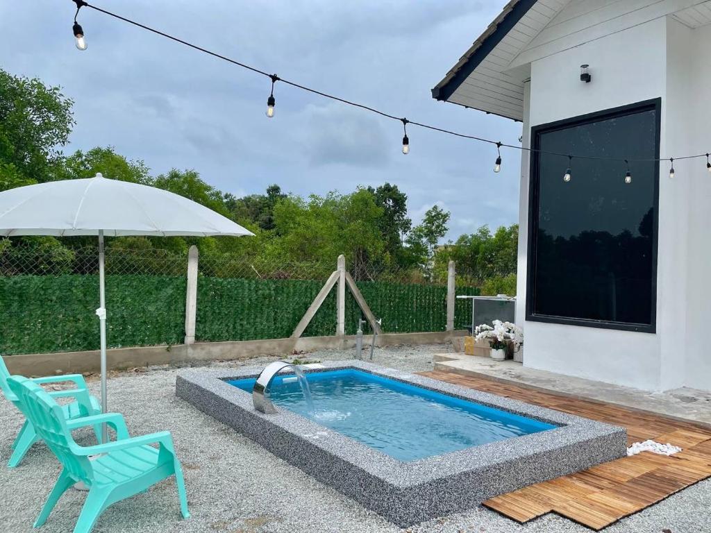 a swimming pool with a chair and an umbrella at Tiny House & Pool 4 pax 3 mins Merang Jetty in Setiu