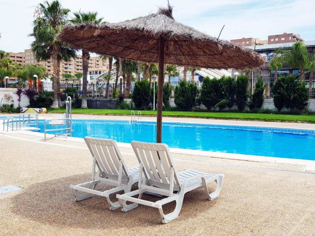 twee stoelen en een parasol naast een zwembad bij Apartamento Trebol 2 in Oropesa del Mar