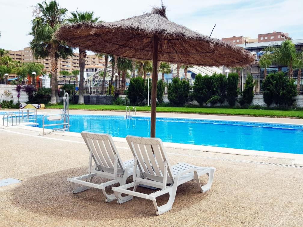 two chairs and an umbrella next to a pool at Apartamento Trebol 2 in Oropesa del Mar