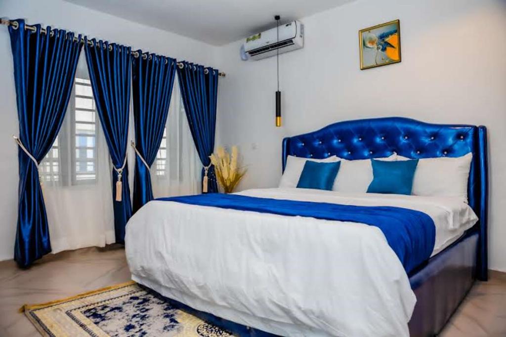 - un lit bleu et blanc dans une chambre avec des rideaux bleus dans l'établissement El Elyon Hotel and Suites, à Lagos