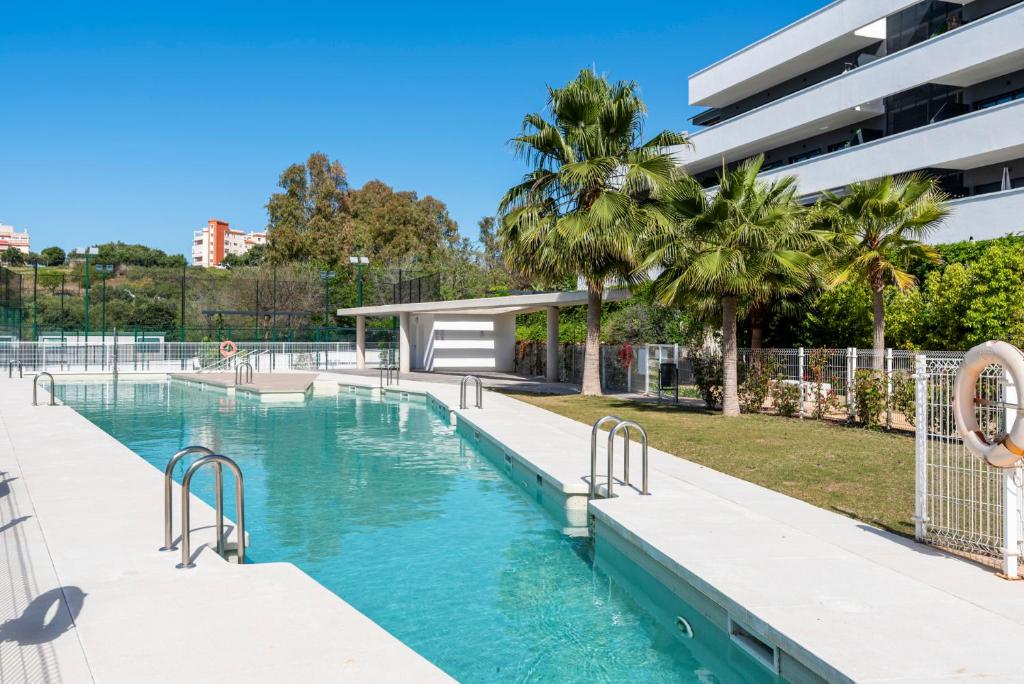 una piscina en un complejo con árboles y un edificio en Stunning flat with pool and padel in Wellingtonia M4, en Estepona