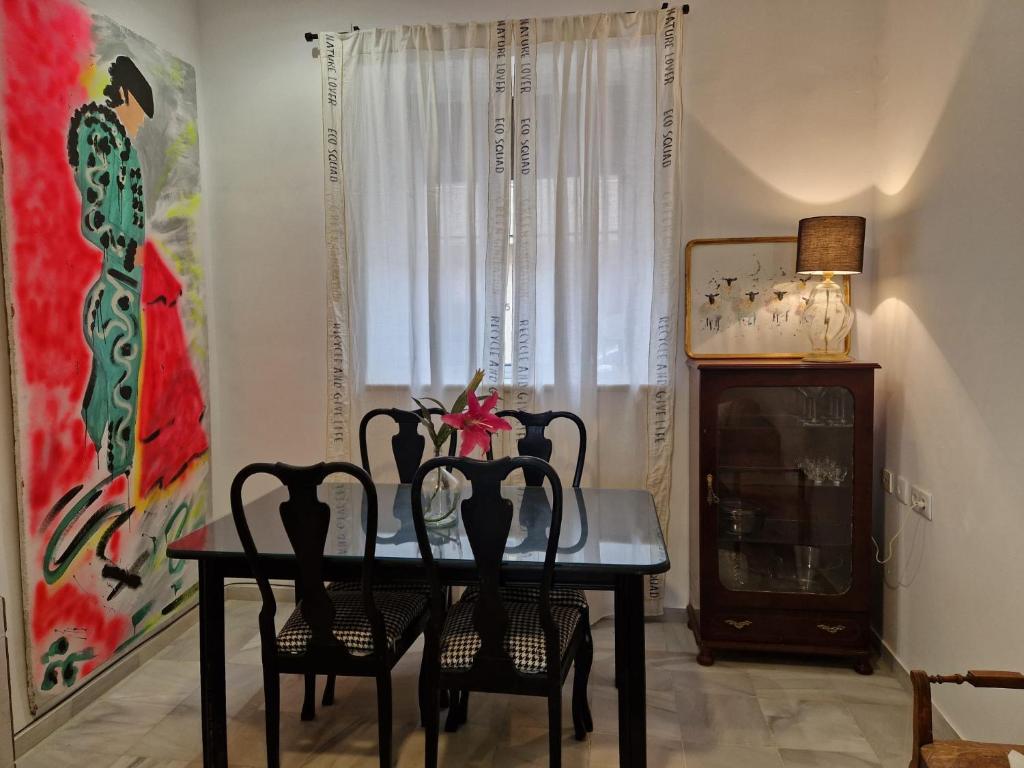 uma sala de jantar com uma mesa e quatro cadeiras em Calzada 10 em Sevilha
