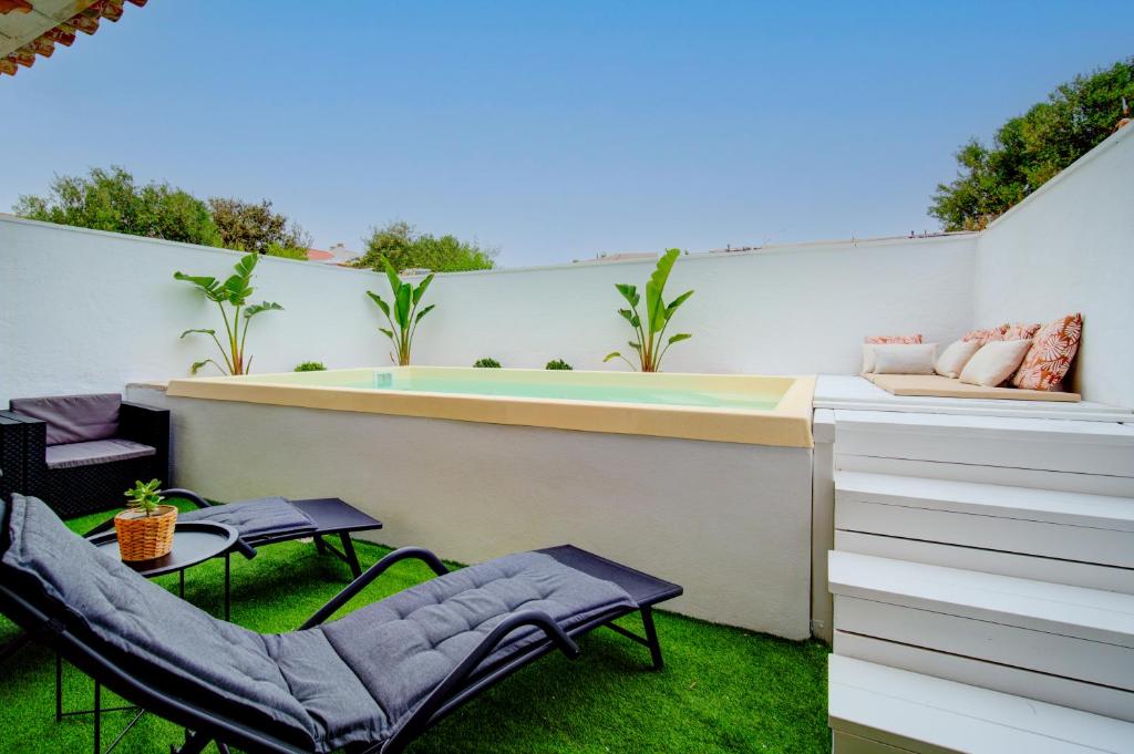 um pequeno quintal com uma banheira de hidromassagem e cadeiras em Casa con Piscina climatizada, Jacuzzi, Billar, Aire Acondicionado em Sant Lluis