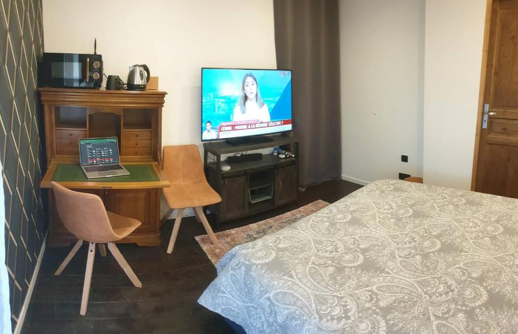 a room with a bed and a television and a table with a laptop at Chambre à la campagne in Mézières-sur-Couesnon