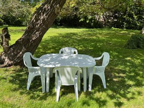 una mesa y dos sillas sentadas junto a un árbol en Appartement en campagne, en Berville-sur-Mer