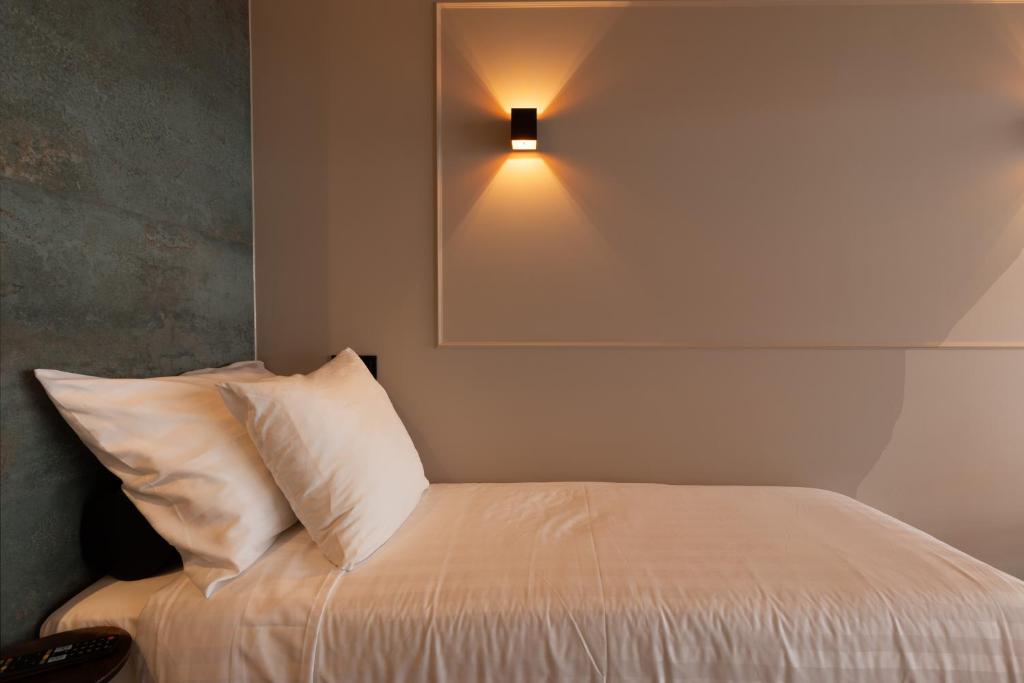 una camera da letto con un letto con una luce sul muro di Midtown Hotel Triple Room ad Amsterdam