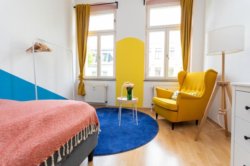 a bedroom with a bed and a yellow chair at FULL HOUSE STUDIOS - Paulus Apartment - Nespresso inklusive in Halle an der Saale