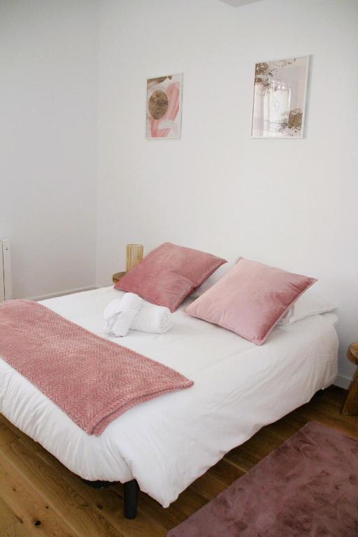 - un lit blanc avec 2 oreillers roses dans l'établissement Flik-en-flac - Appartement à 20m de la plage, à Roscoff
