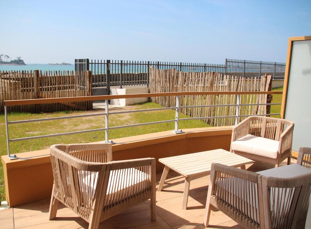 d'un balcon avec des chaises et des tables offrant une vue sur l'océan. dans l'établissement La Madrague - front de mer, accès privé plage et place de parking, à Roscoff