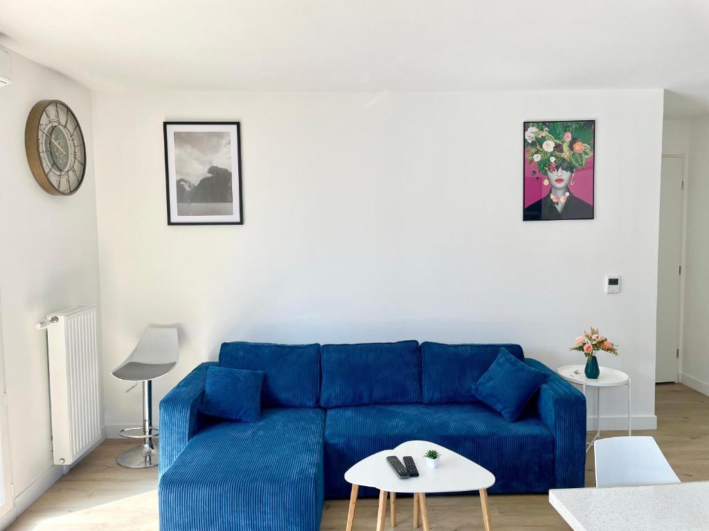 a living room with a blue couch and a table at Chambre Confort - Douche Privative - Jardin - Parking Gratuit in Argenteuil
