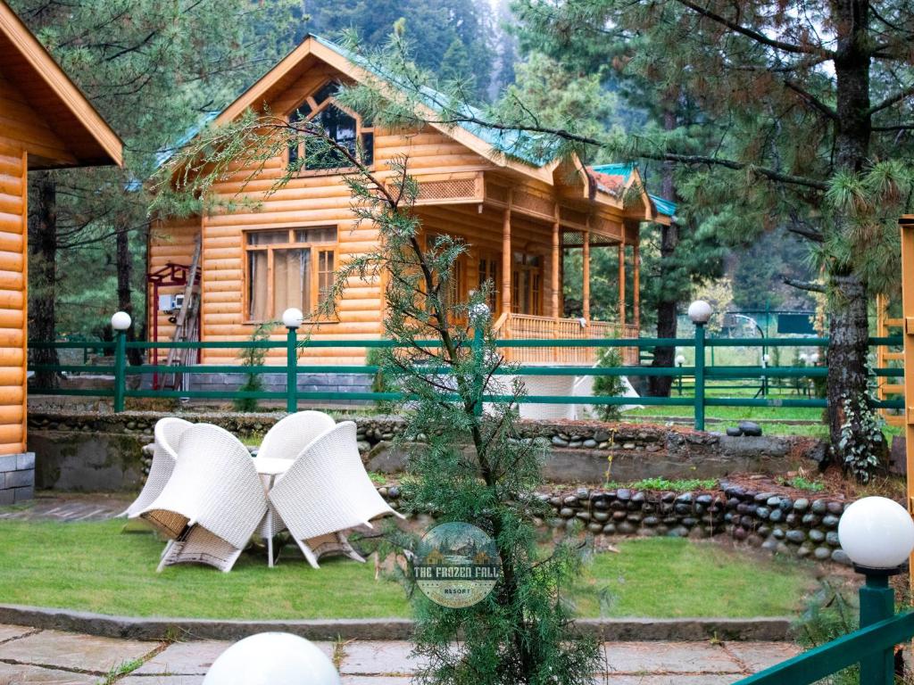 a wooden house with white chairs in front of it at Dawat-e-Drung by FrozenFall Resort in Gulmarg