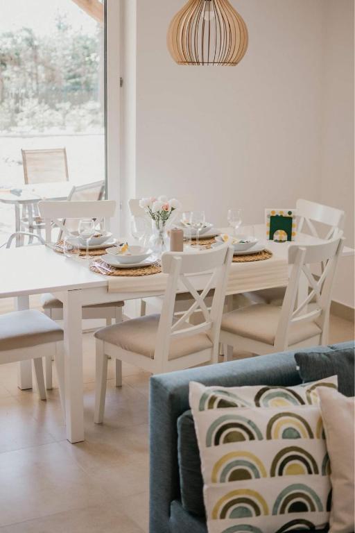a white dining room with a white table and chairs at Green House Relax in Płaska