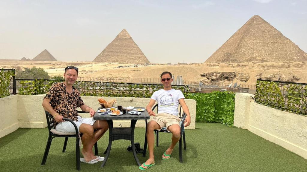 two men sitting at a table in front of the pyramids at Solima pyramids in Cairo