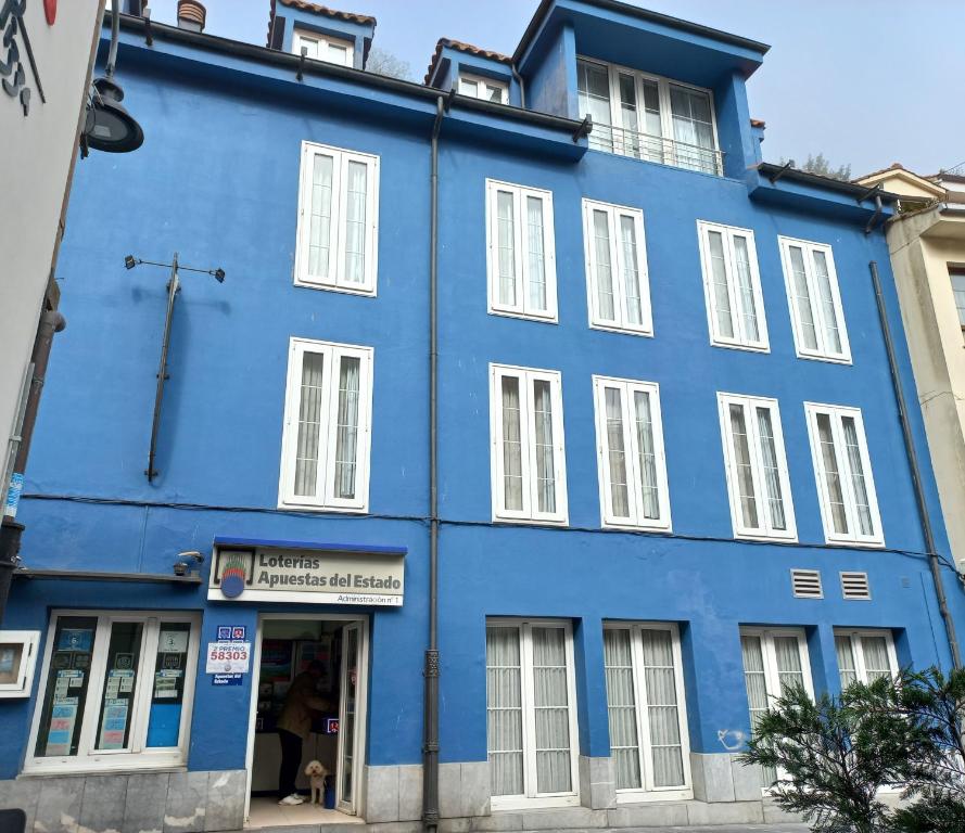 niebieski budynek z białymi oknami na ulicy w obiekcie Isabel Rooms - Suarez Inclán 38 w mieście Cudillero