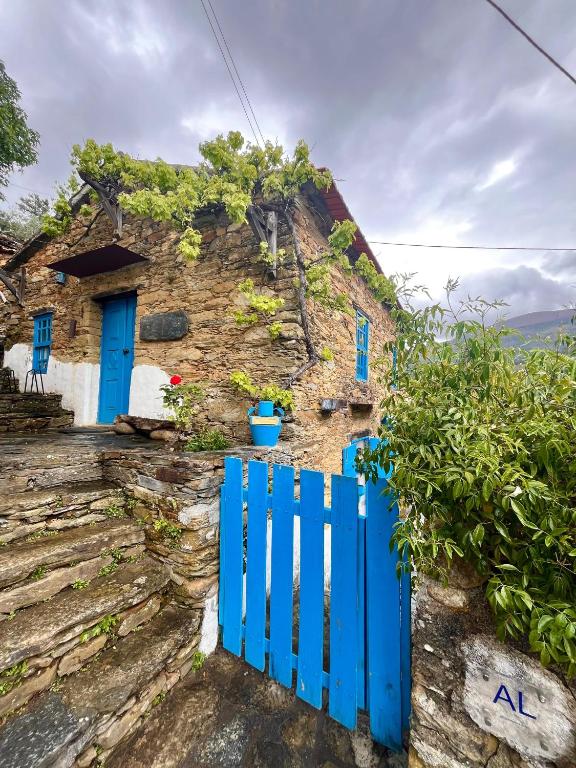 a blue gate in front of a stone house with blue doors at Refúgio da Estrela in Aguincho