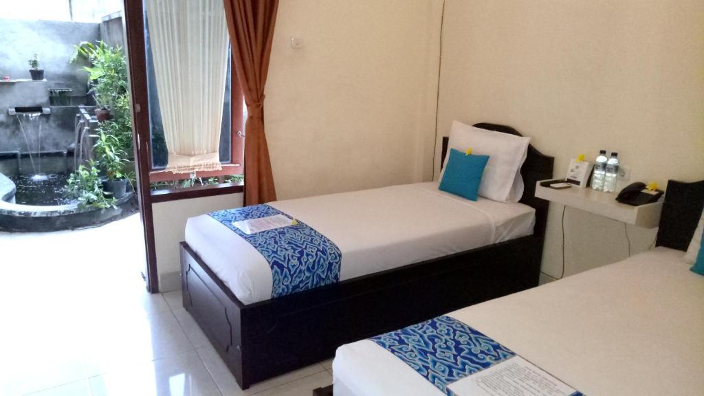 Djembank Hotel في Tjakranegara: غرفة صغيرة بسريرين ونافذة