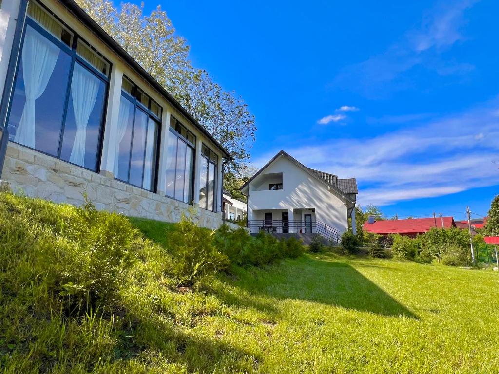 une maison avec de grandes fenêtres sur une pelouse dans l'établissement Casa Maria Sarata Monteoru, à Sărata-Monteoru