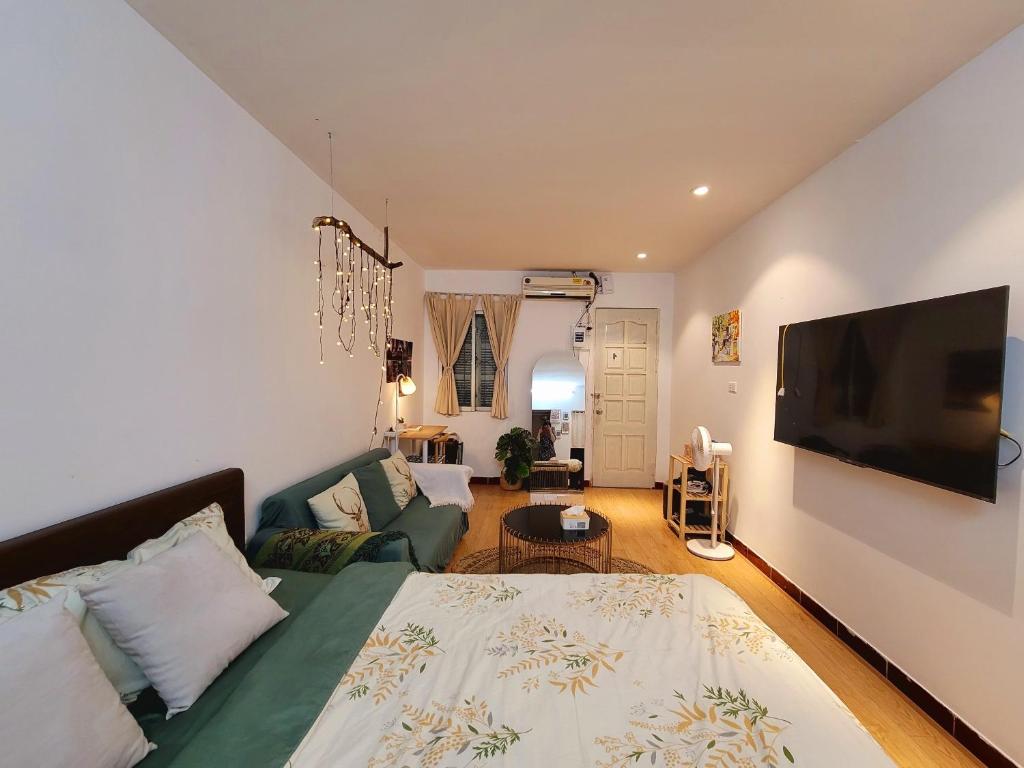 - un salon avec un lit et une télévision à écran plat dans l'établissement Tiny Homes- Vintage Apartments, à Hanoï