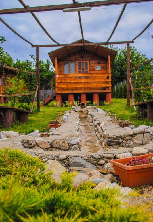 a log cabin with a stone path leading to a house at Căsuțele dintre vii in Runcu