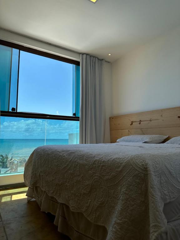 een slaapkamer met een bed en een groot raam bij Pousada Aloha in Maceió