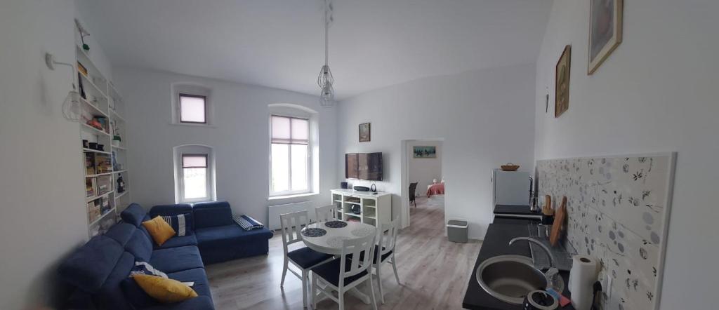 Una sala de estar con un sofá azul y una mesa. en Apartament Przy Marinie, en Giżycko