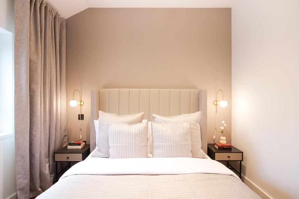 1 dormitorio con 1 cama blanca y 2 mesitas de noche en Smithfield by The Heim Residences, en Mánchester